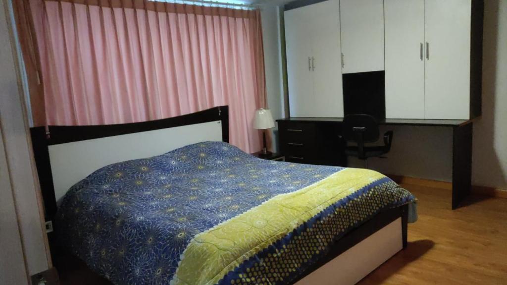 a bedroom with a bed with a blue and yellow blanket at El palacio de cristal in Sangolquí