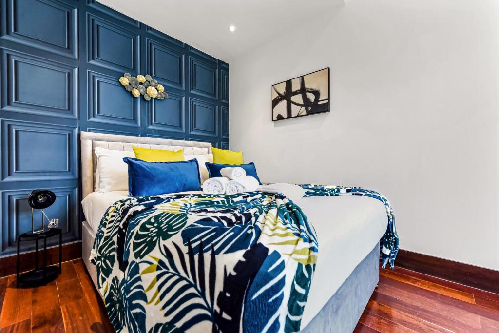 Comfortable 3 Bedroom Apartment in Greater London في Hanwell: غرفة نوم بجدران زرقاء وسرير مع لحاف