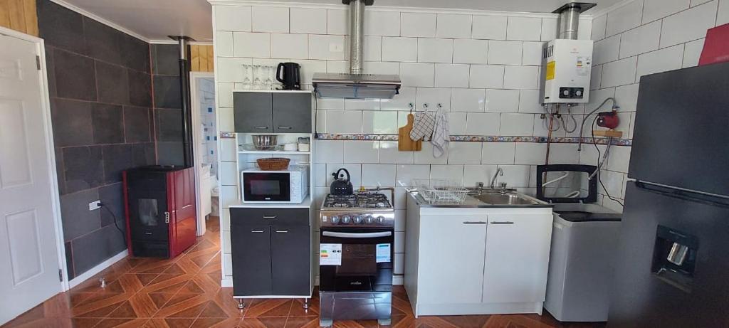 małą kuchnię z białymi szafkami i kuchenką w obiekcie cabaña los teros w mieście Coihaique