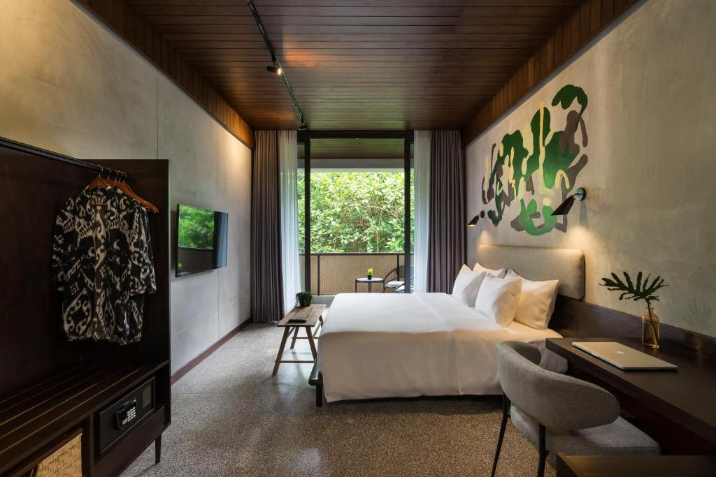 a bedroom with a bed and a desk and a television at ARTOTEL Haniman Ubud in Ubud