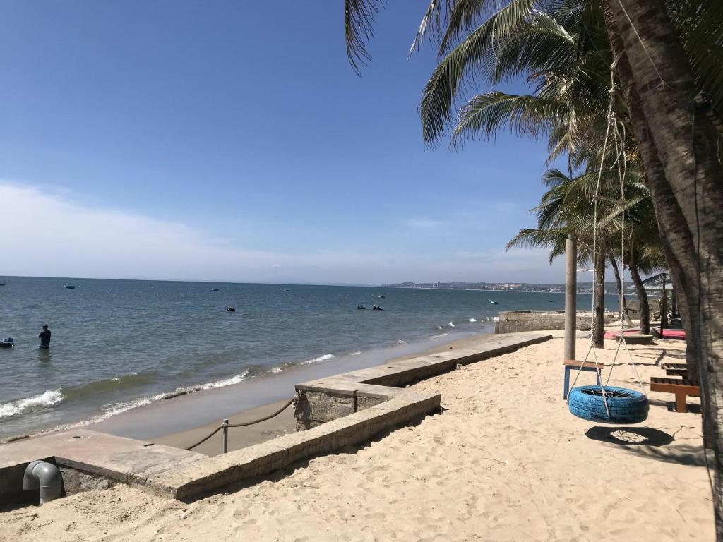 una playa de arena con palmeras y el océano en Nhat Quang Bungalow en Mui Ne