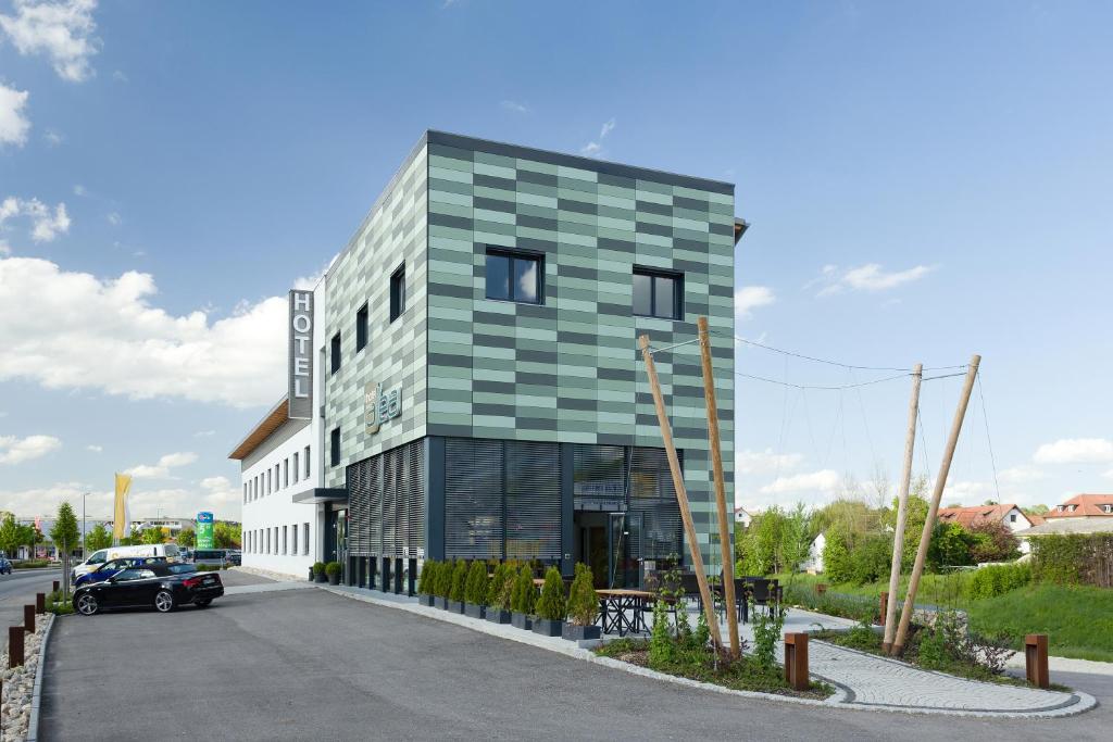 ein grünes Gebäude mit einem davor geparkt in der Unterkunft Hotel Alea City in Pfaffenhofen an der Ilm