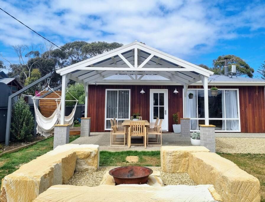 a pavilion with a table and chairs in front of a house at Salty Air Cottage in Bream Creek