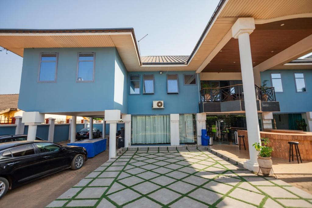 una casa azul con un coche aparcado delante de ella en Beauty Hotel, en Accra
