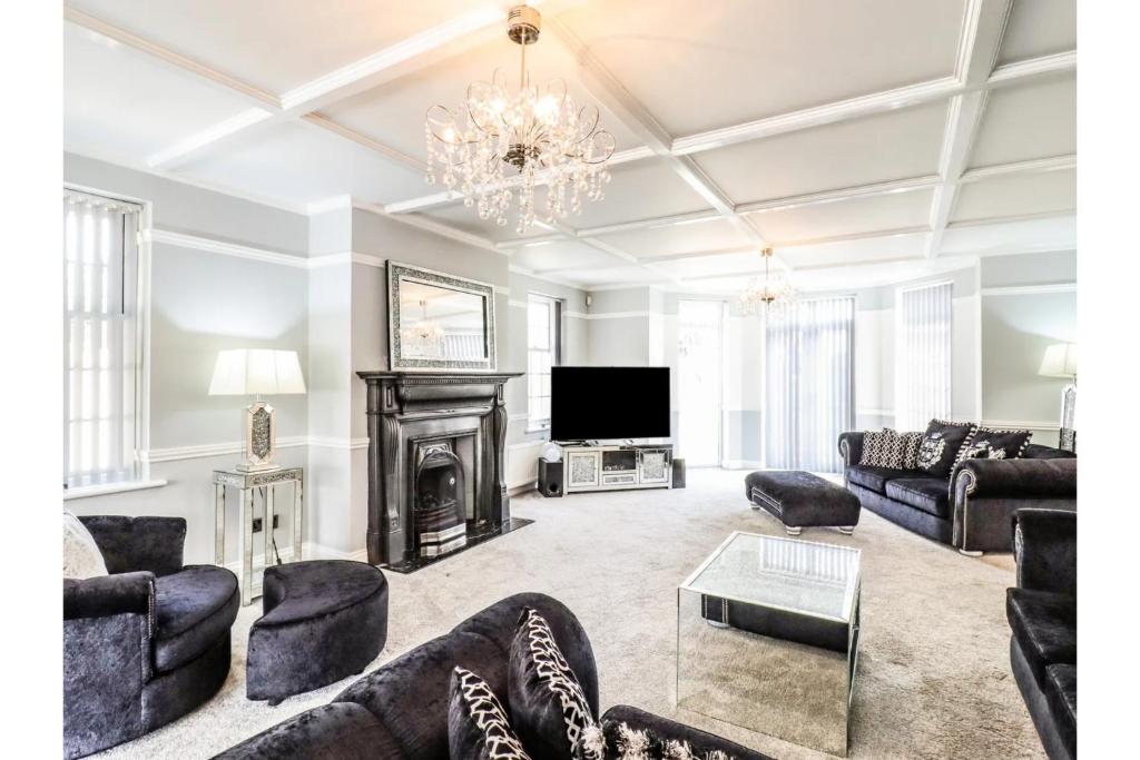 ein Wohnzimmer mit Sofas, einem Kamin und einem TV in der Unterkunft Luxurious 6 Bedroom Villa with Pool Sleeps 12 in Canvey Island