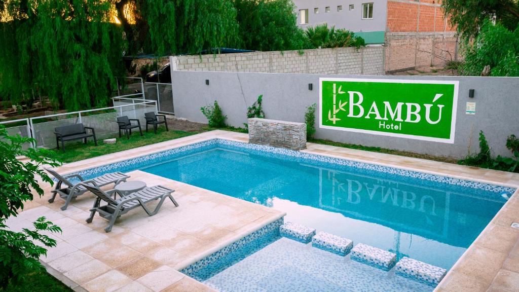 a swimming pool with a sign next to a building at Bambú Hotel in Chepes