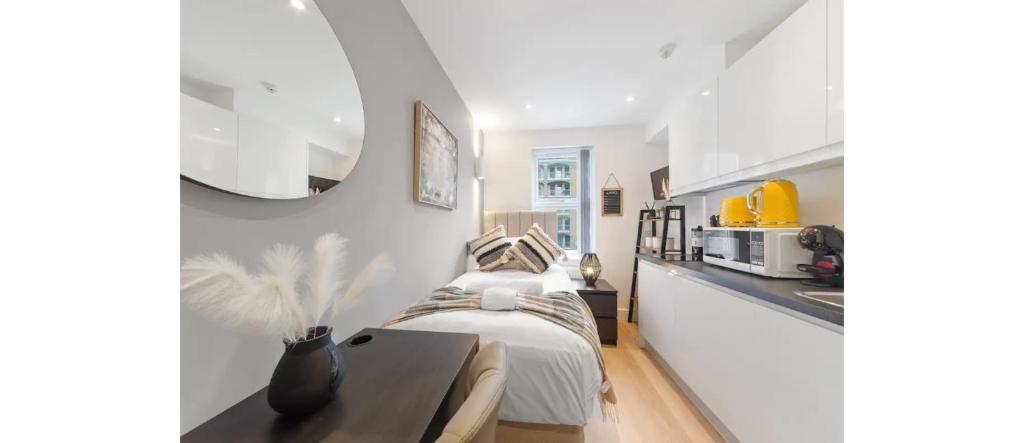 a white bedroom with a bed and a kitchen at The *Best* Airbnb for Transport in London! Promise in London