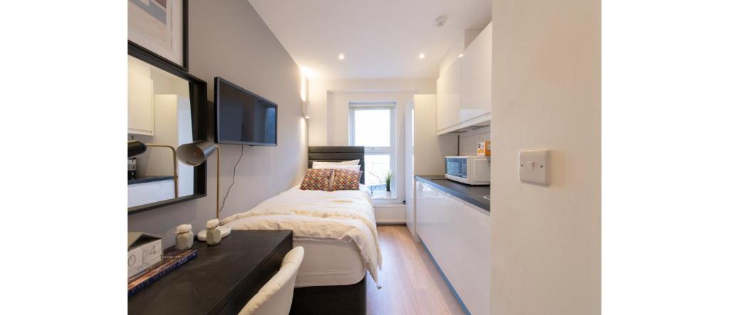 a small bedroom with a bed and a desk at Cozy-Bnbs Tiny and Perfect Studio Apartment in London
