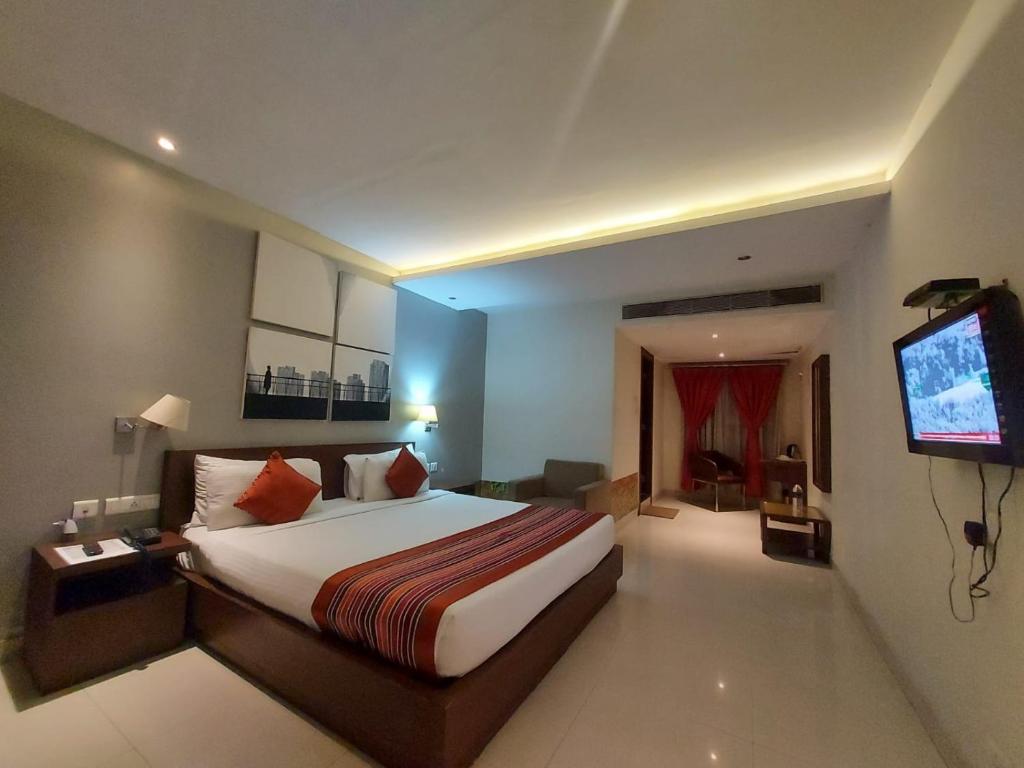 um quarto de hotel com uma cama e uma televisão em Orbit Hotel em Bāghdogra