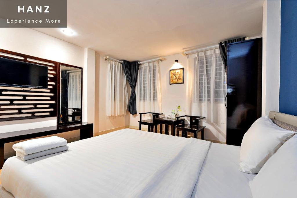 een slaapkamer met een groot bed en een tafel bij HANZ Hotel SEN Ben Thanh in Ho Chi Minh-stad