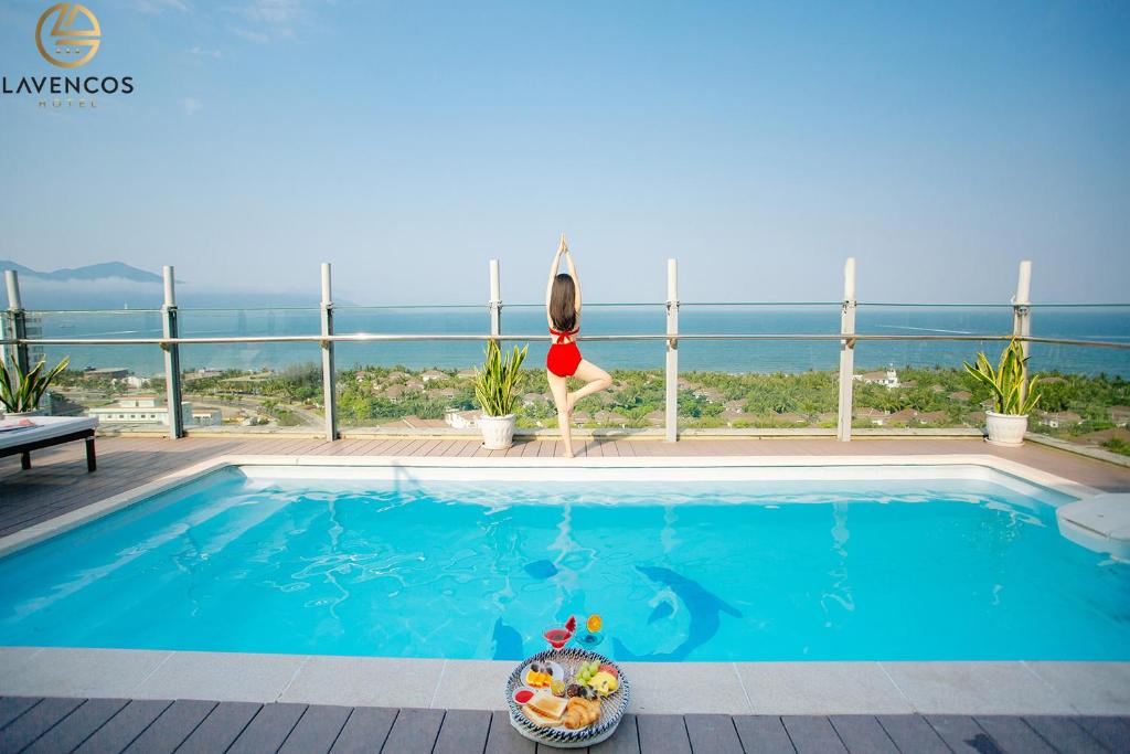 una donna è in piedi di fronte a una piscina di Lavencos Hotel Da Nang a Da Nang