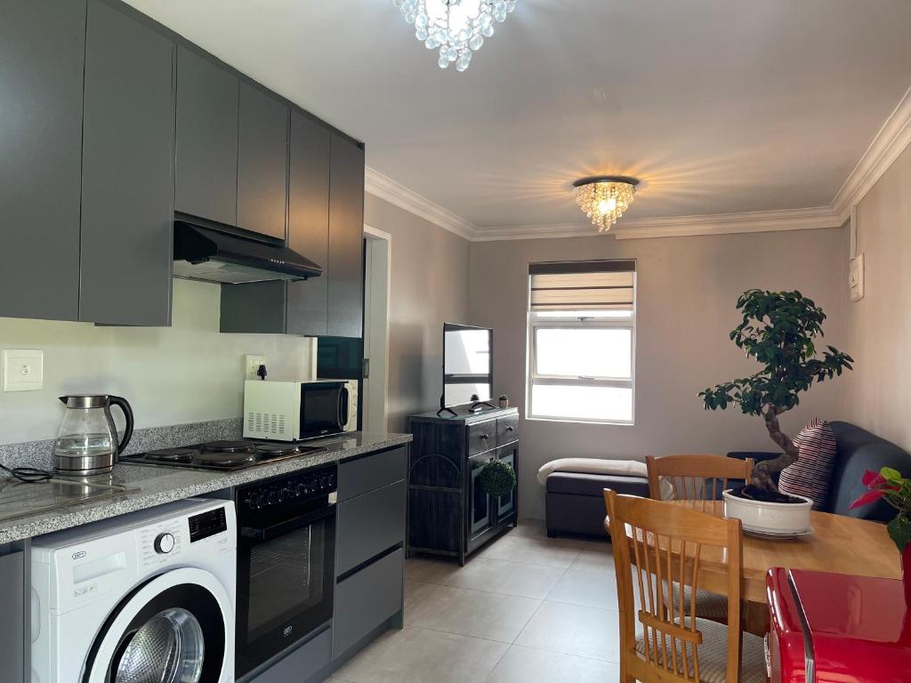 eine Küche mit einer Waschmaschine und ein Esszimmer mit einem Tisch in der Unterkunft Hill Luxury Cottage in Roodepoort