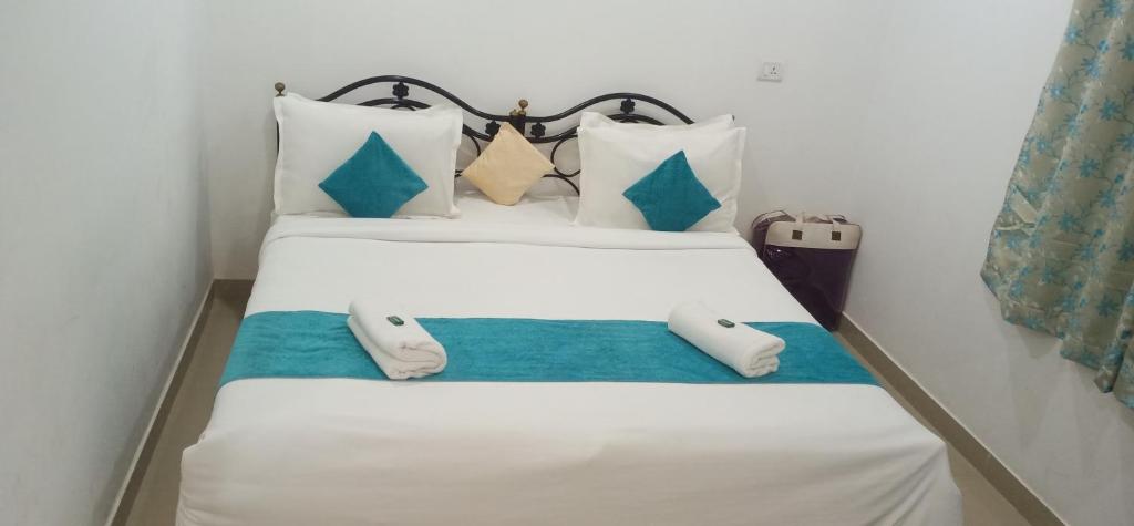 1 dormitorio con 1 cama con sábanas y almohadas blancas en CASA SOMANJO INN, en Calangute