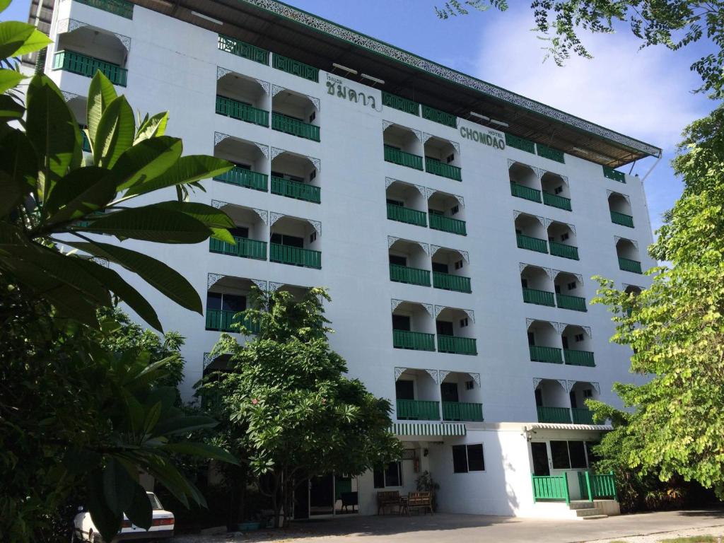 un edificio blanco con balcones y árboles en Chomdao Hotel, en Rayong