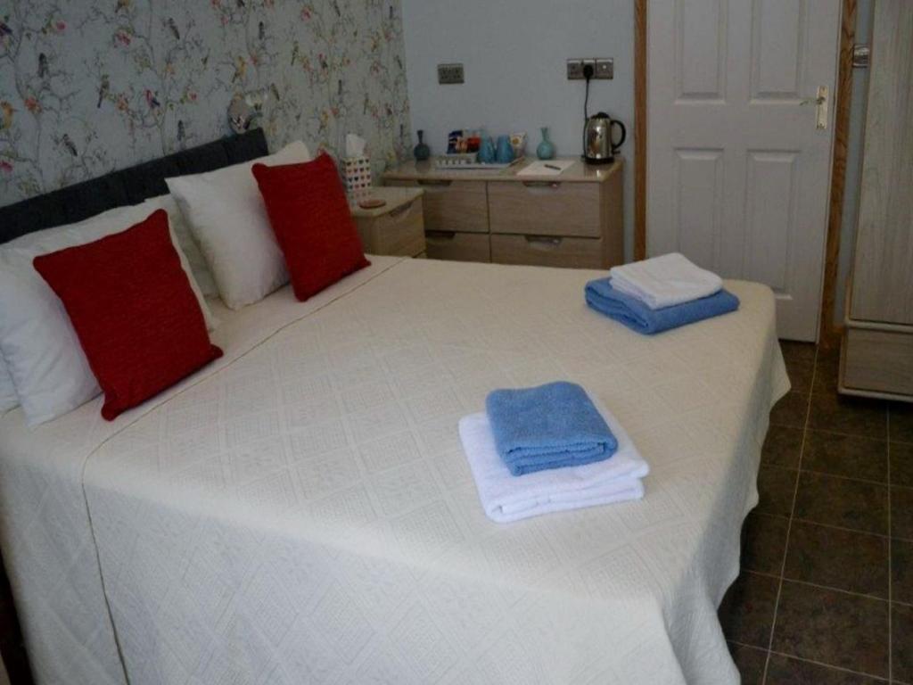 Una cama blanca con toallas rojas y azules. en No9 Guesthouse, en Hunstanton