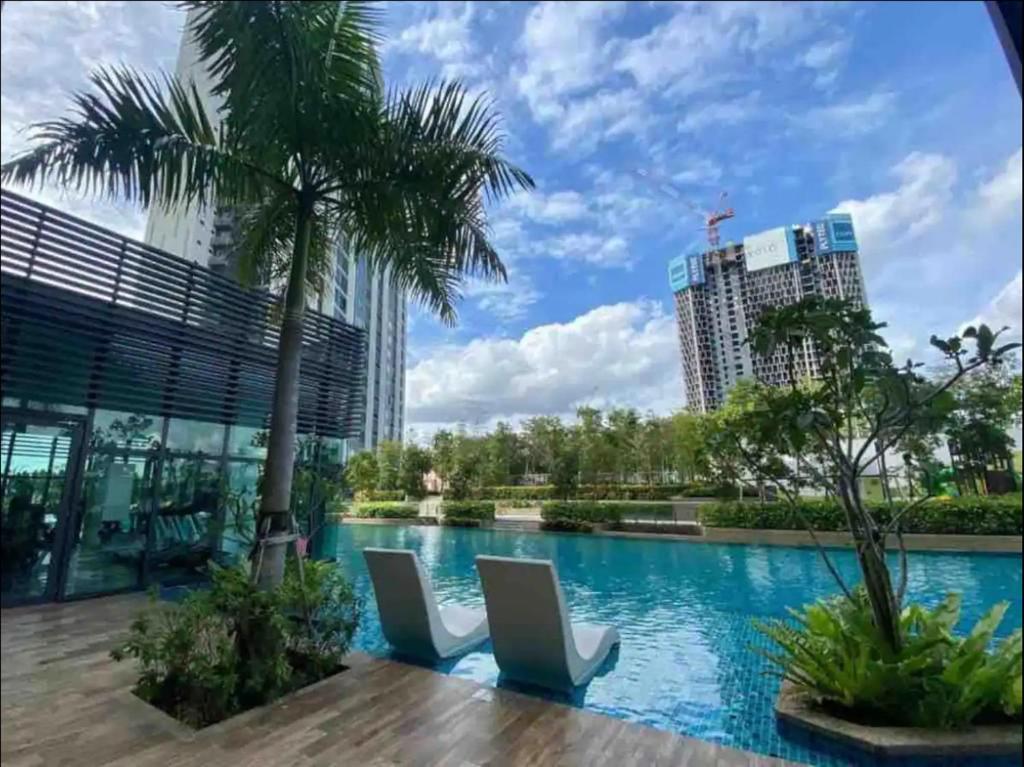 een zwembad met een palmboom en gebouwen bij Greenfield Residence Comfort Stay Near sunway pyramid, sunway college, one academy, taylors uni in Petaling Jaya