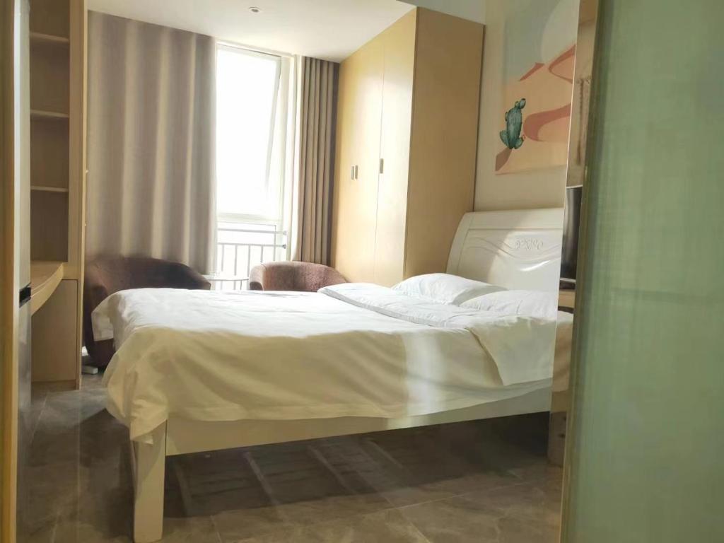 1 dormitorio con cama blanca y ventana en Yangzhou Xianyun Apartment en Yangzhou