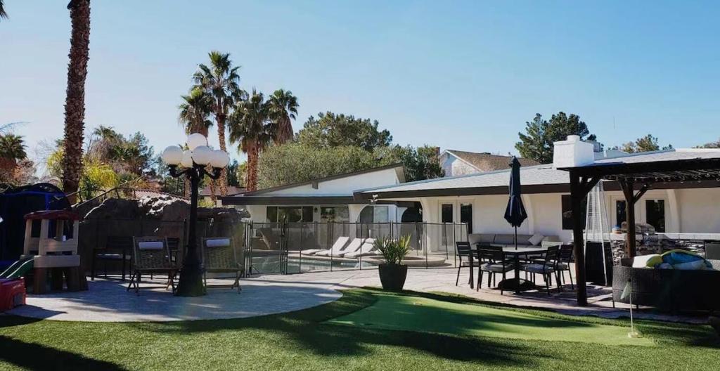 a patio with a table and chairs and a house at Luxury Villa, with bonus pool house, Private Pool, Hot tub, rock water fall and slide, putting green, basketball, shuffle board, play gym, privately gated on circular driveway. in Las Vegas