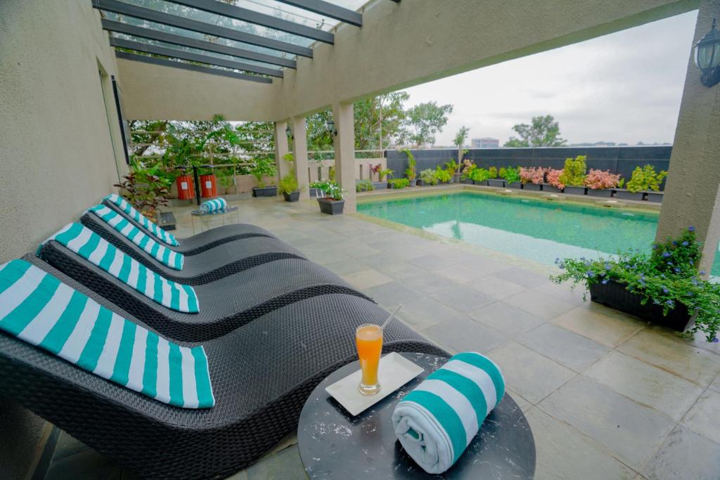 バンガロールにあるLazdana Hotel Bangaloreのパティオ(ソファ付)、スイミングプールが備わります。