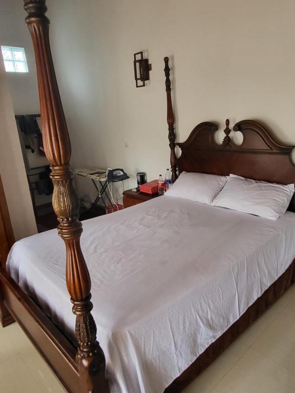 - une chambre avec un grand lit en bois et des draps blancs dans l'établissement Shanicky villa, à Kandana