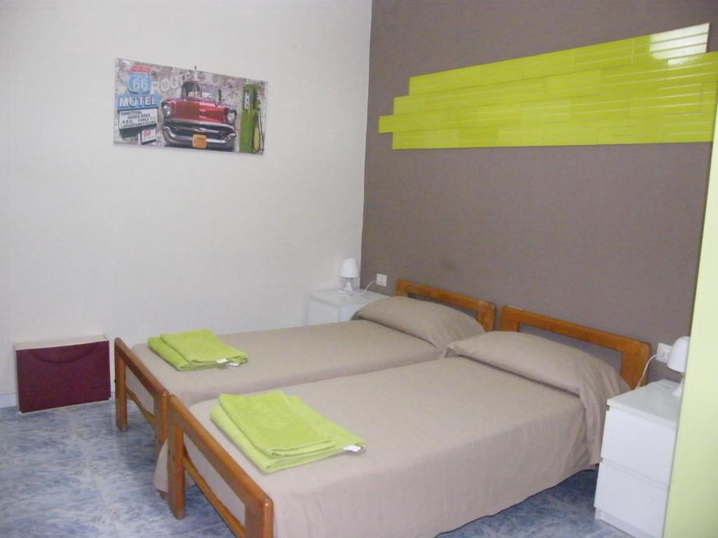 2 Betten in einem Zimmer mit grünen Handtüchern darauf in der Unterkunft Alborada B&B in Salerno