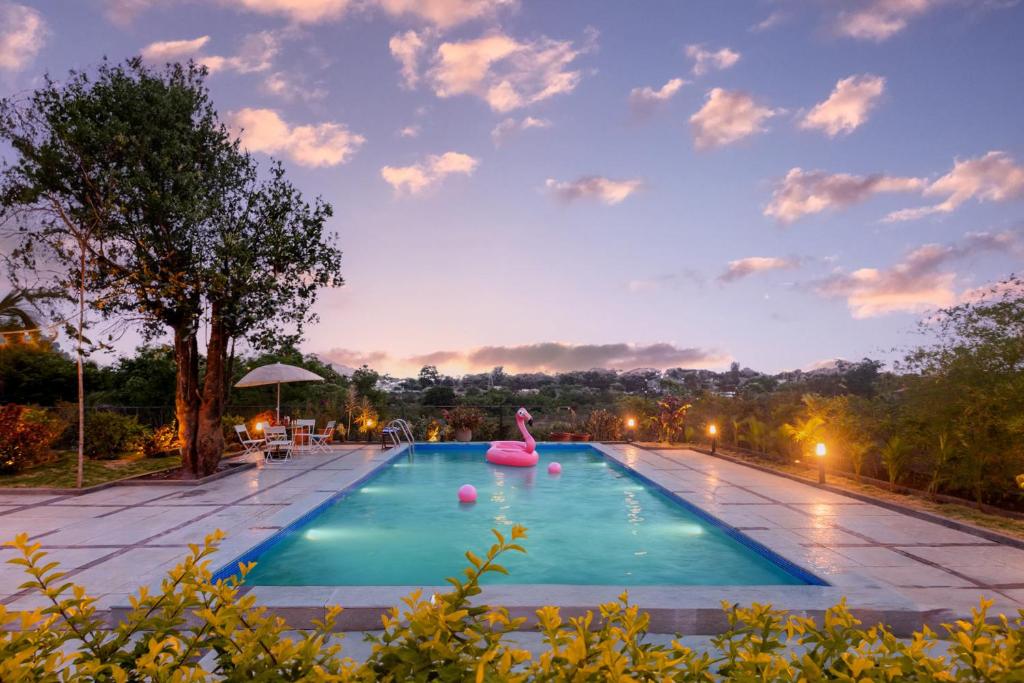 a large swimming pool with a pink raft in it at Villa Aangan by StayVista - A heritage charm with Swimming pool, Gazebo, Projector room & Indoor games in Lonavala