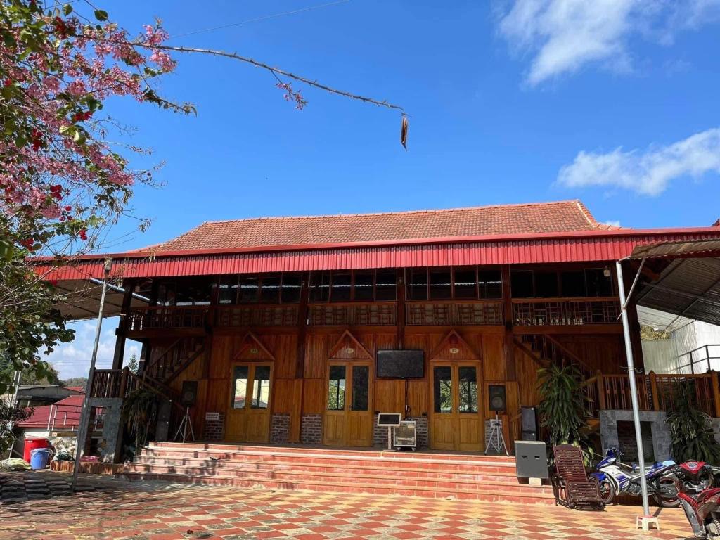 a large wooden house with a red roof at Homestay Cao Nguyên Mộc Châu in Mộc Châu