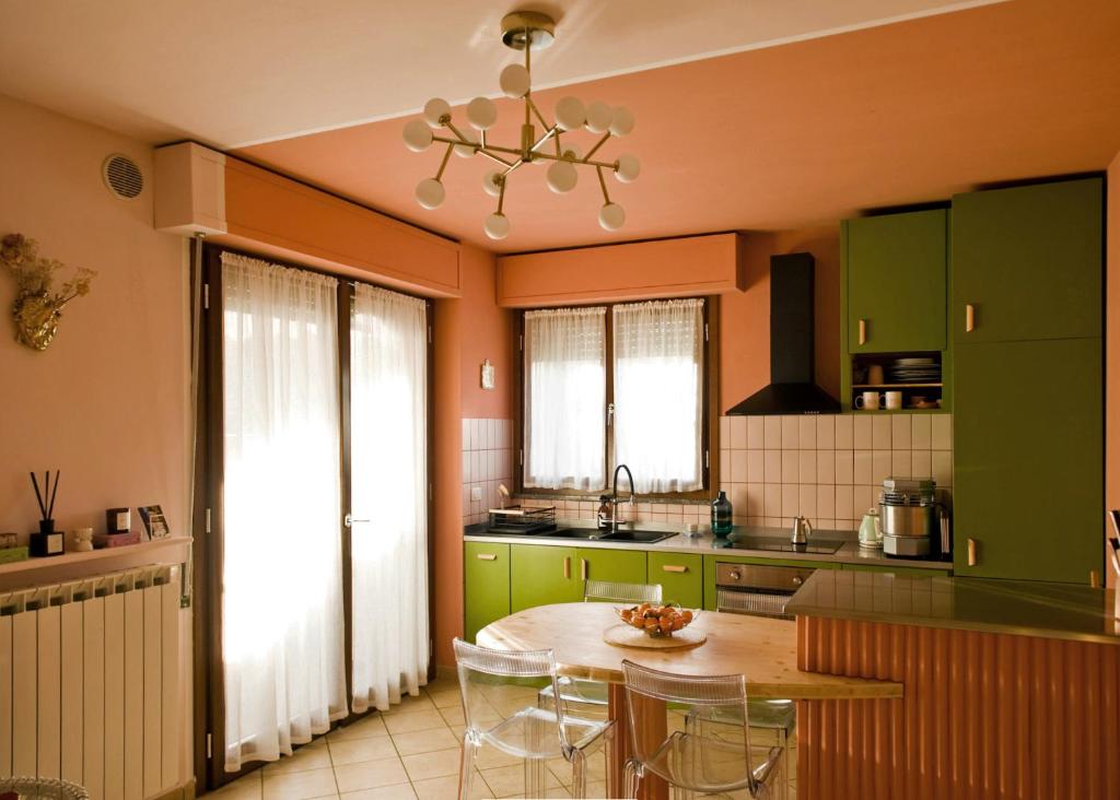 una cucina con armadi verdi e un tavolo con sedie di Apartment with Garden a Romano di Lombardia