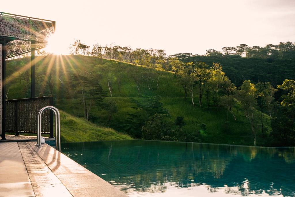 a swimming pool with the sun shining on a hill at Skyloft Kandy by Aaradhya in Kandy
