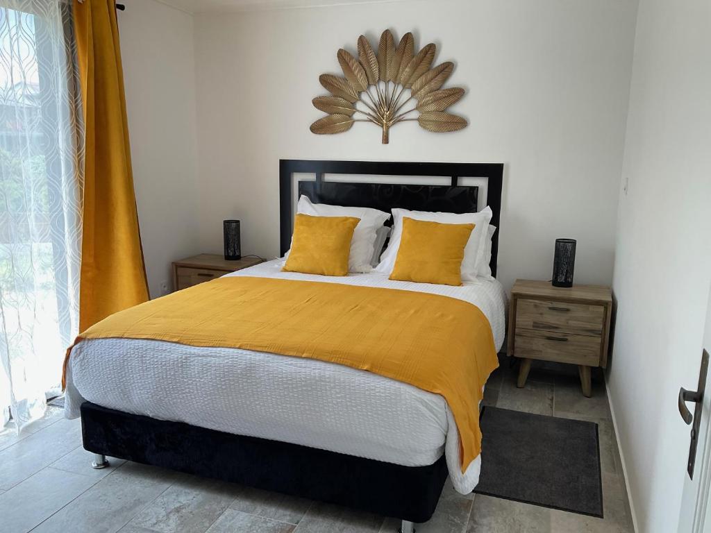- une chambre avec un grand lit et des oreillers jaunes dans l'établissement Les Villas de Bella, à Saint-Louis