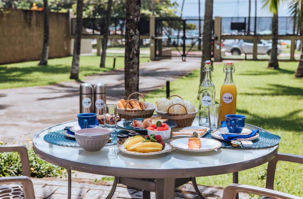 a table with plates of food and bottles of wine at Vila M Suítes ᵇʸ ᴬᴸᴱᴮᴬᴴᴸᴵ in Ilhabela