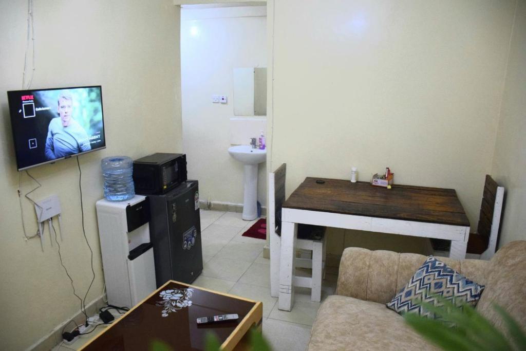 ein Wohnzimmer mit einem Sofa, einem Tisch und einem TV in der Unterkunft Cutie homes in Nairobi
