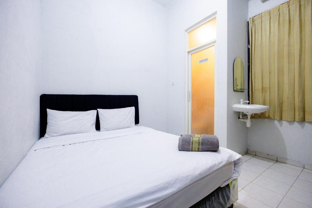 um quarto com uma cama branca e uma cabeceira preta em Marcello Residence Siwalankerto near Petra University Surabaya Mitra RedDoorz em Surabaya