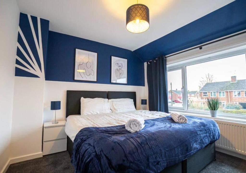 um quarto com uma cama com paredes azuis e uma janela em 4 Bedroom Apartment with non-smoking room - Big special offer for long stays em North Hykeham