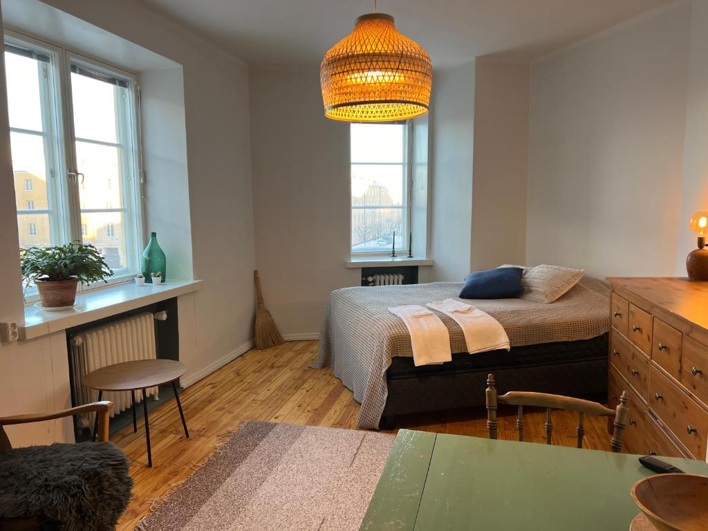 1 dormitorio con cama, mesa y ventanas en Valoisa & Mukava koti vallilassa en Helsinki