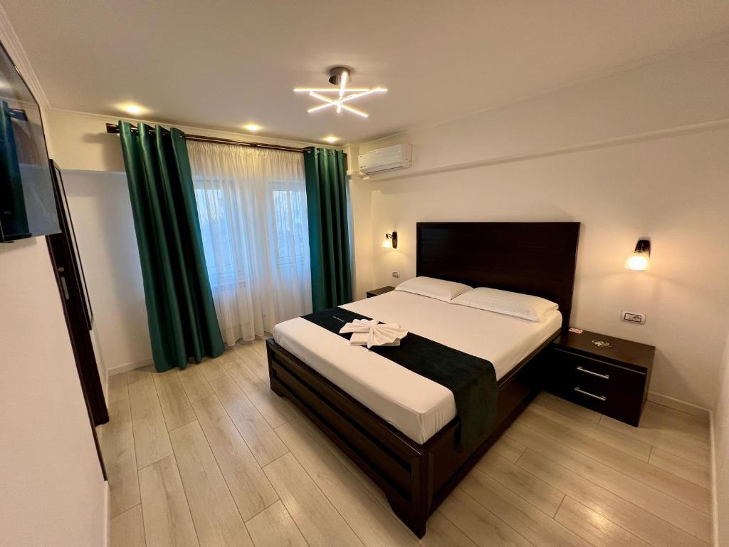 a bedroom with a large bed with green curtains at Garsoniera SARA in Târgu Jiu