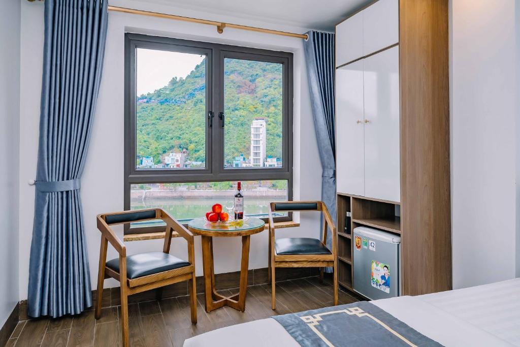 カットバ島にあるBao Phuc Hotelのテーブルと椅子2脚、窓が備わる客室です。