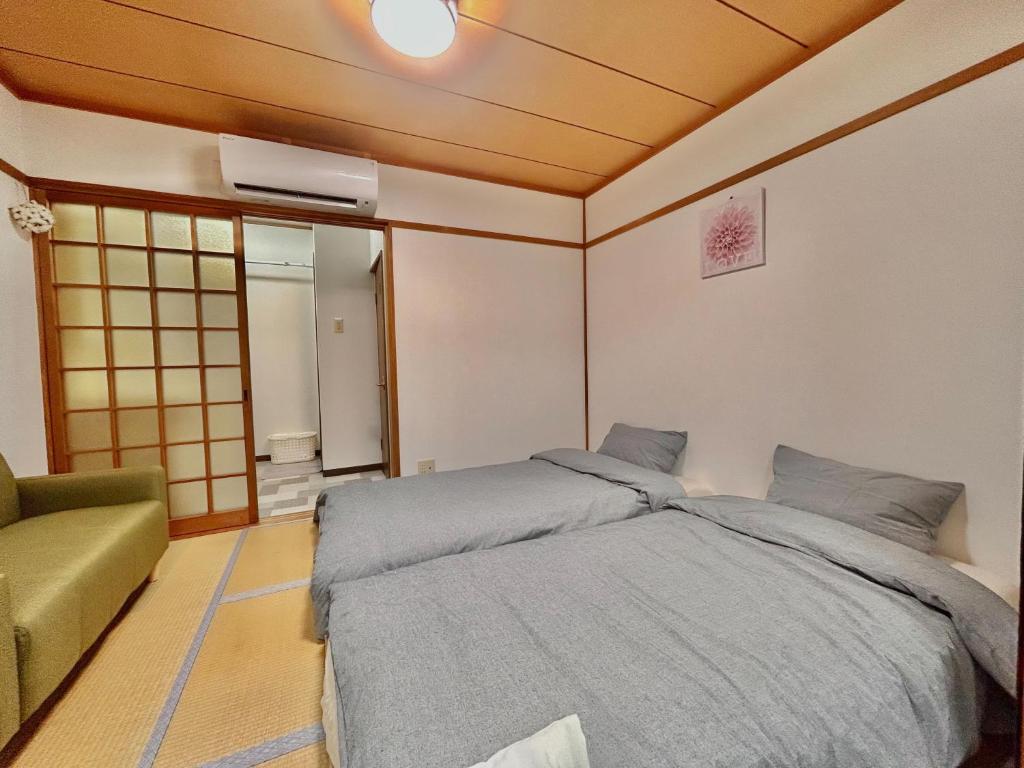 a bedroom with a large bed and a couch at 空港＆海遊館直通、2WAYアクセス便利、過客ノ家ー弁天町 in Osaka