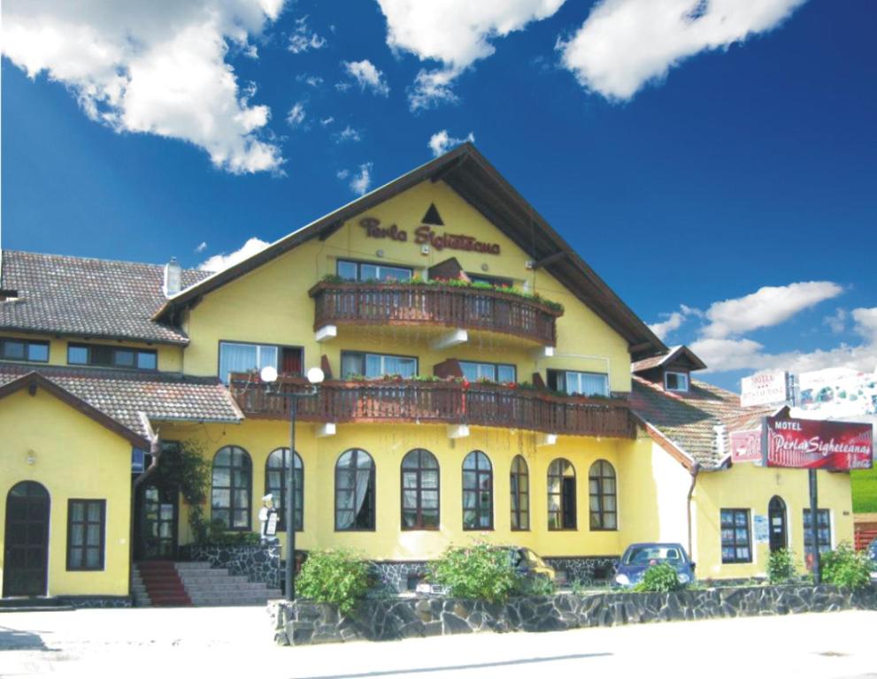 a yellow building with a balcony on top of it at Motel Perla Sigheteana in Sighetu Marmaţiei