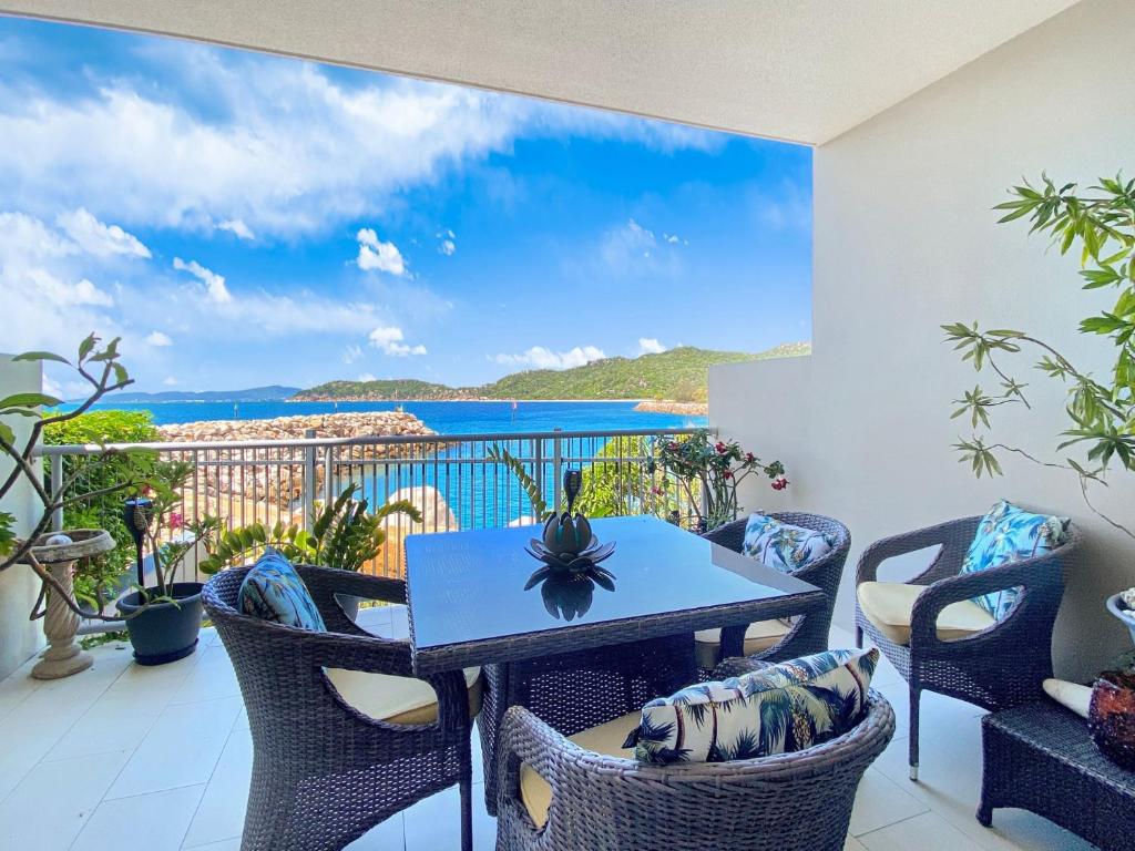 a table and chairs on a balcony with a view of the ocean at 1 Bright Point Apartment 3104 in Nelly Bay