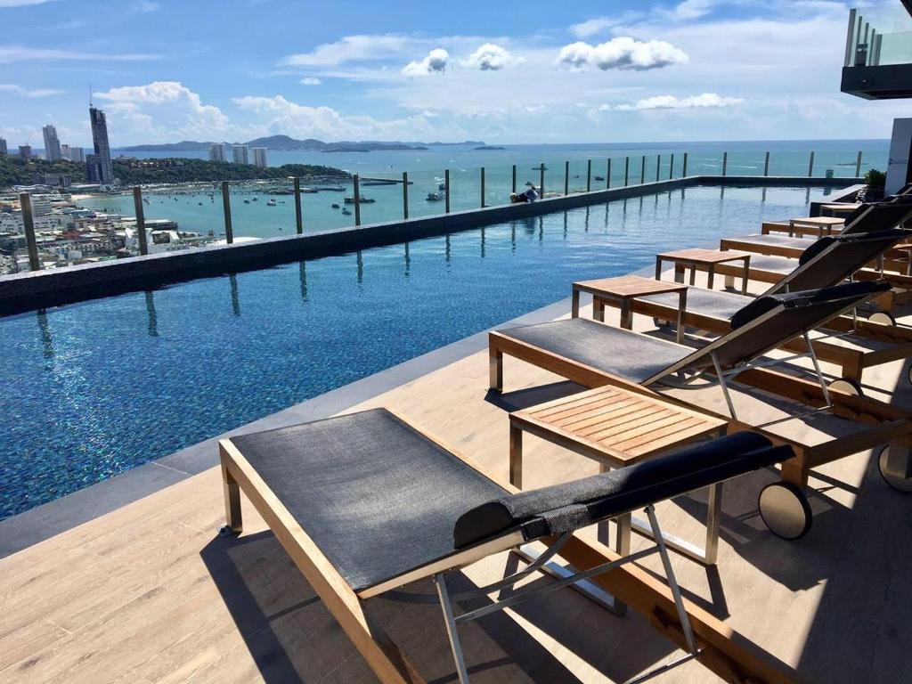 a row of chaise lounges on the edge of a swimming pool at The Base Central Pattaya by Leya in Pattaya Central