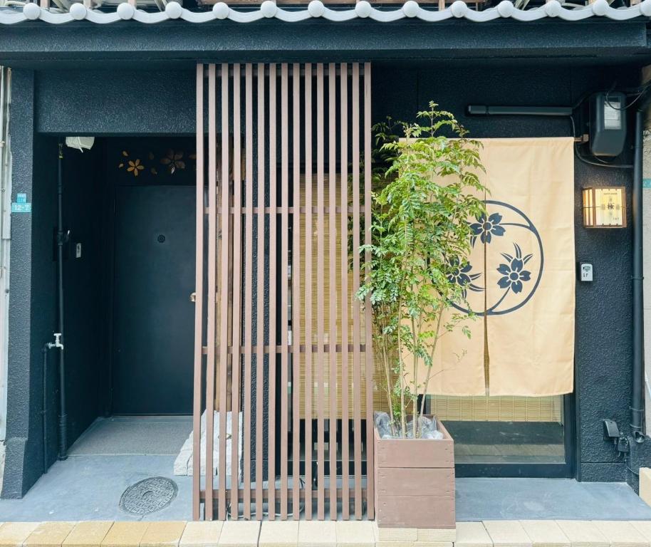 uma porta de um edifício com uma planta na frente dele em Ebisu-Sakura 恵美須～桜 em Osaka