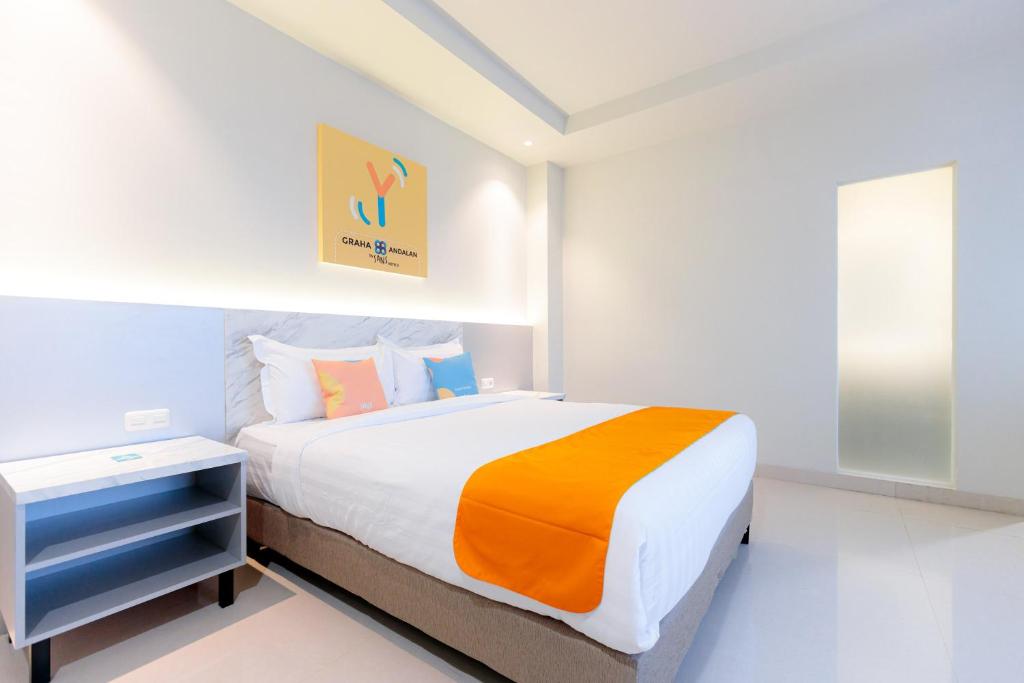 een slaapkamer met een bed met een oranje en witte deken bij Sans Hotel 88 Andalan Surabaya by RedDoorz in Surabaya