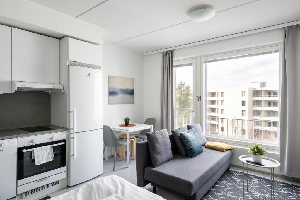 a living room with a couch and a kitchen at Hiisi Homes Espoo Center in Espoo