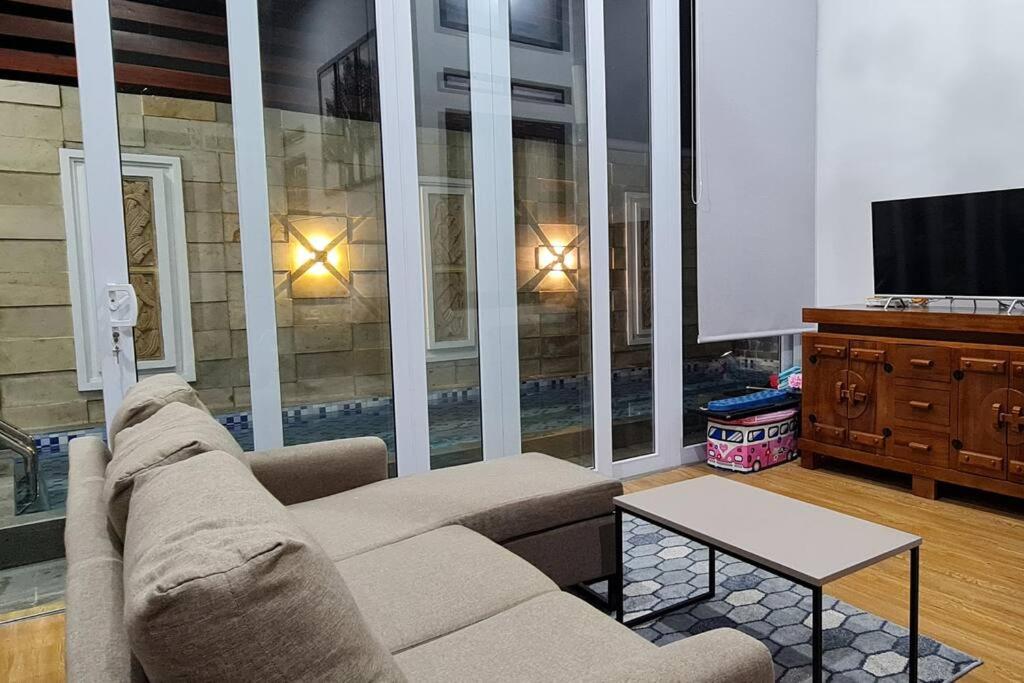 a living room with a couch and a tv at Shazia House - Modern and Cozy Home with 3 Bedrooms and Private Pool in Tanjungkarang