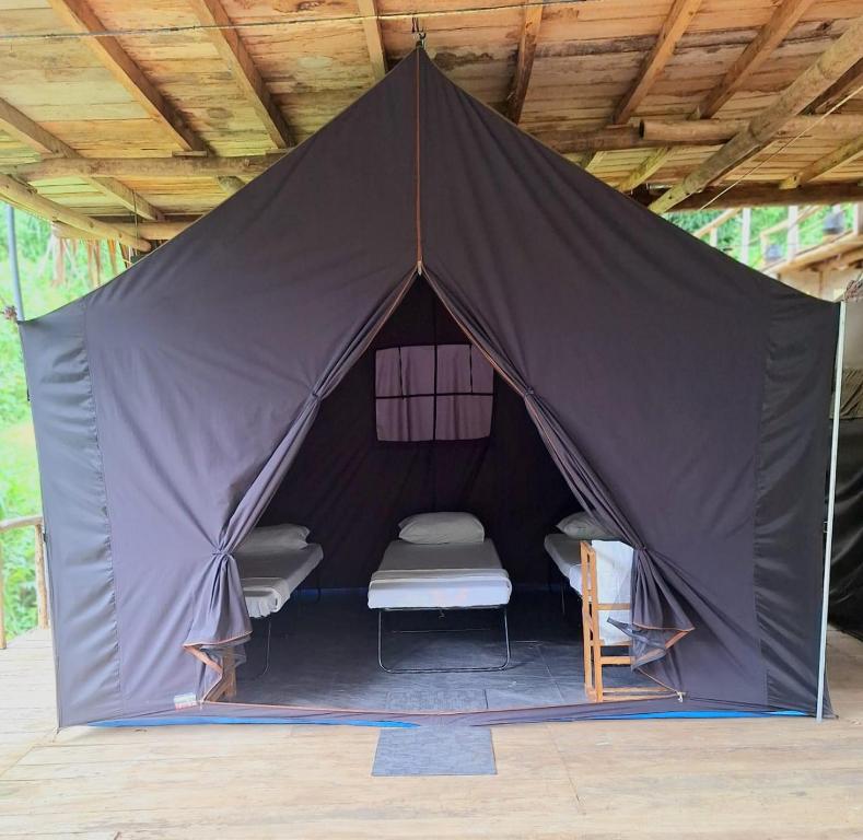 uma tenda com duas camas e uma cadeira em Ella Nine Arch Glamp Site em Ella