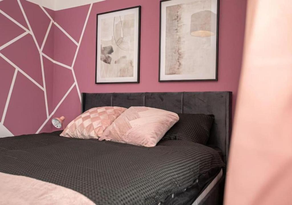 a bedroom with a black bed with pink walls at 3 Bedroom Apartment with non-smoking room - Special big offer for long-term stays in Lincolnshire