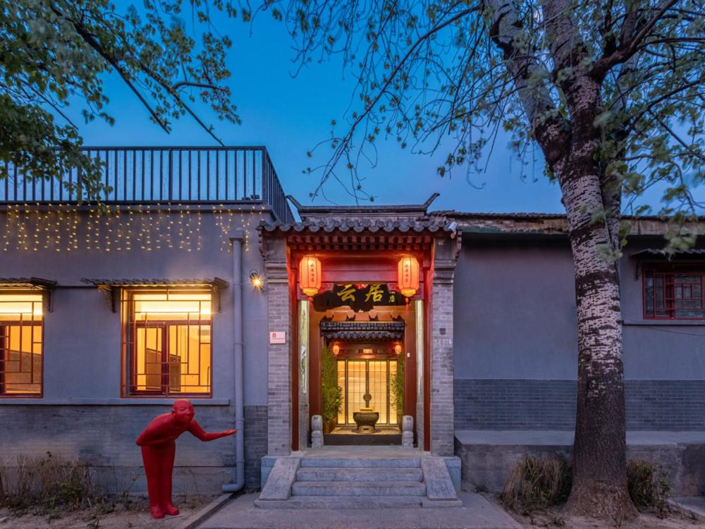 a person standing in front of a house at Yunju Hotel Beijing Yonghe Palace Guijie Siheyuan in Beijing