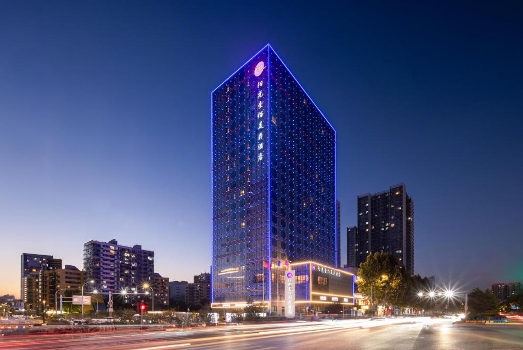 a tall blue building in a city at night at Grand Mercure Jinan Sunshine in Jinan