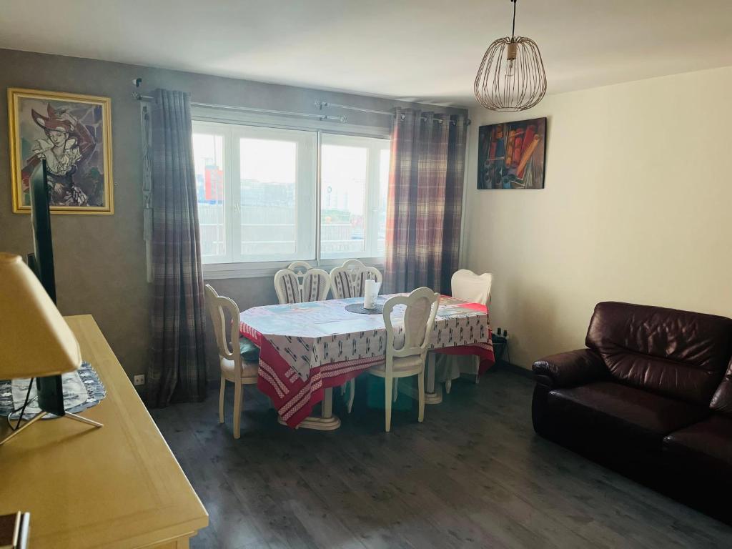 un salon avec une table, des chaises et un canapé dans l'établissement Booking, à Clichy